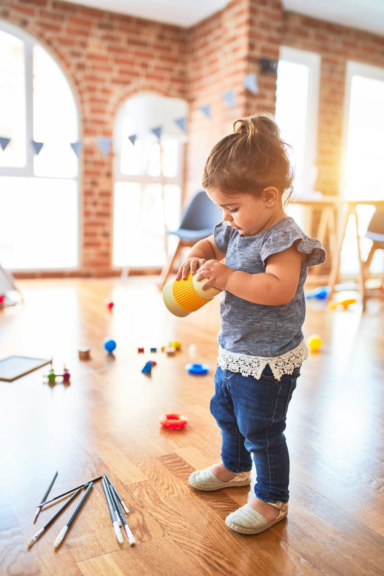 A toddler exploring toys in a sunlit playroom